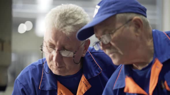 Engineers Repair and Discuss CNC Milling Machine at a Heavy Industry Factory. Employee Carefully