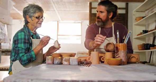 Male and female potter painting pots