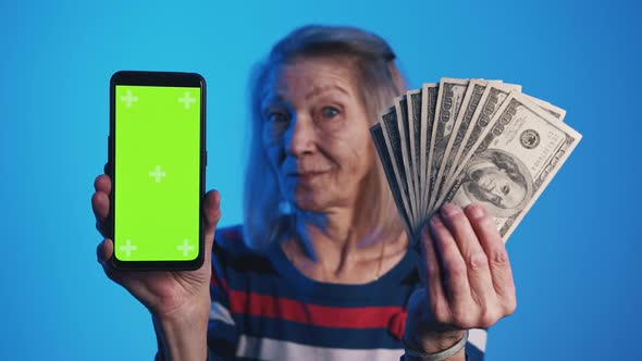 Old Woman Holding Smartphone with Green Screen and Dollar Bills