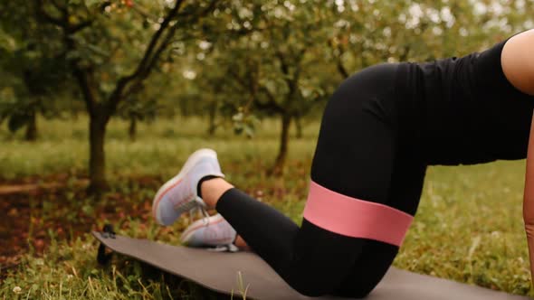 Young Woman Working Out Resistance Bands in Sportswear Outdoors