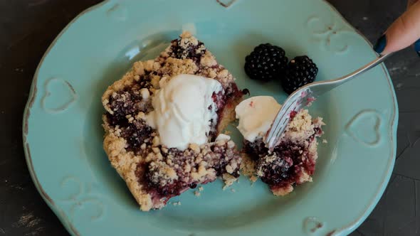 Piece of cake with blackberries and ice cream on a blue plate