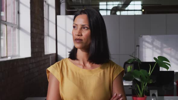 Portrait of mixed race businesswoman looking ahead then shifting gaze to camera and smiling