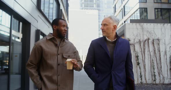 Two Men of Different Ages and Nationalities are Talking Walking in Office Center