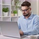 A business man works remotely behind a laptop at a desktop in the interior. - VideoHive Item for Sale