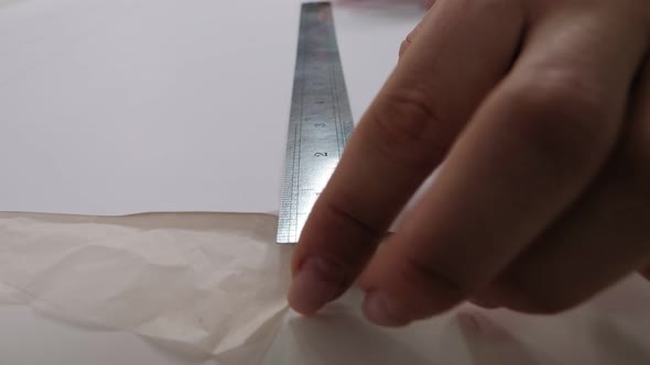 A Seamstress with a Ruler Draws a Pattern on Paper with a Pencil