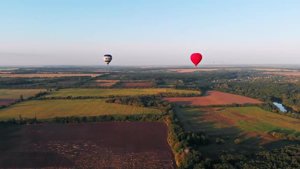 A beautiful red balloon flies in the evening over the river and the city.