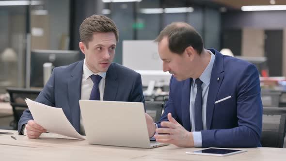 Two Businessman Discussing While Working on Laptop in Office