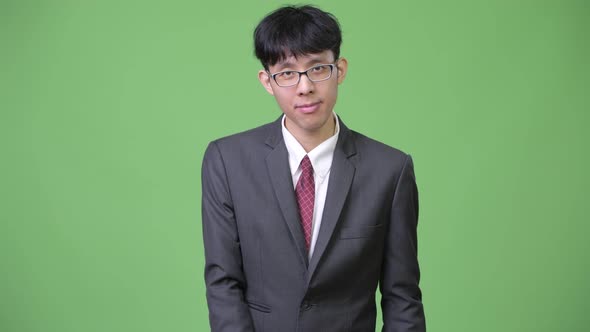 Young Asian Businessman Reading with Clipboard and Shrugging Shoulders