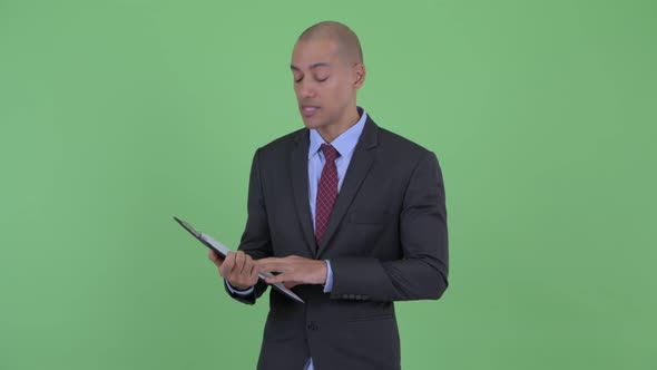 Happy Bald Multi Ethnic Businessman Talking While Holding Clipboard