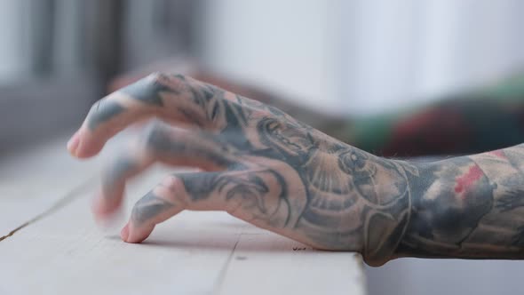 Closeup Side View Male Tattooed Hands with Fingers Tapping on Windowsill