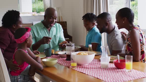 Three generation african american family looking at smartphone and having breakfast together at home