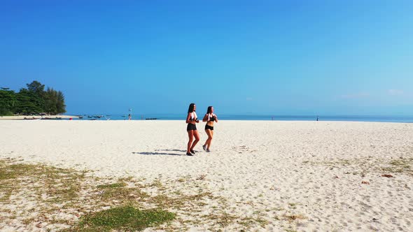 Pretty fun women on holiday in the sun on beach on sunny blue and white sand 4K background