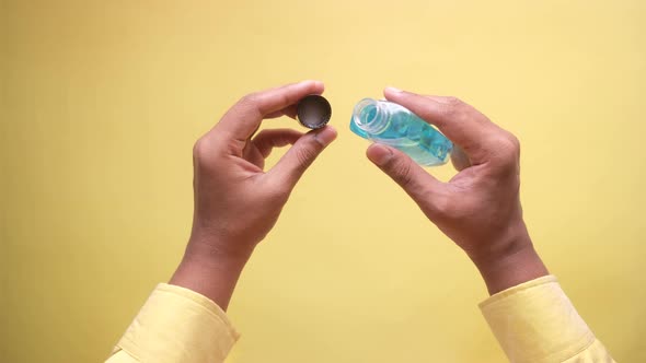 Hand Hold a Mouthwash Liquid Container Against Yellow Background