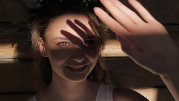 Girl touching the sunlight by hand in her room at home. Happy woman looking at shining sun through h