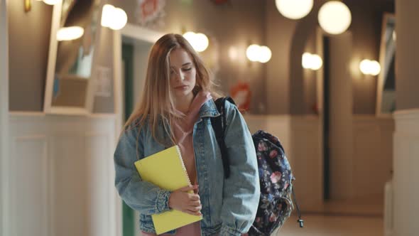 Beautiful Upset Woman Student Walking with Books and Backpack Indoors