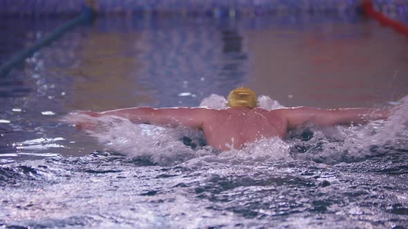 A Man Swimmer in Yellow Cap Swimming on the Track in the Pool