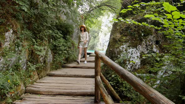 A young girl in shorts walking on a wooden bridge, slow motion