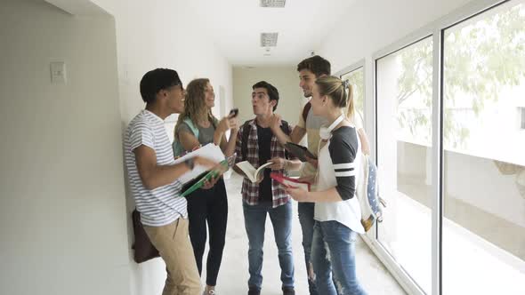 Students talking and giving high-five in college corridor