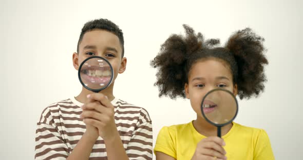 Two Kids with Magnifiers Over White Background