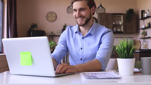 Happy young businessman is analizing financial documents from home during self isolation on laptop