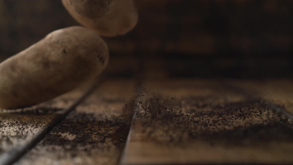 Potatoes falling on wooden table. Slow Motion.