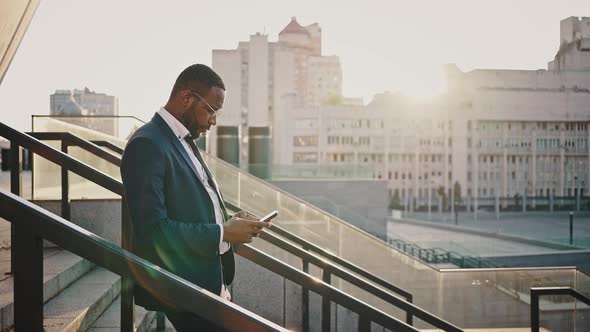 Confident African American Businessman Leaving Office Building in Evening Networking on Cellphone