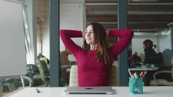 Smiling Satisfied Young Businesswoman Finished Computer Work Stretching Sitting at Workplace Desk at