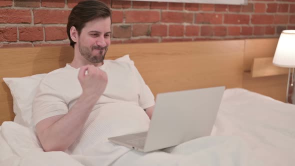 Casual Young Man Having Wrist Pain Working on Laptop in Bed