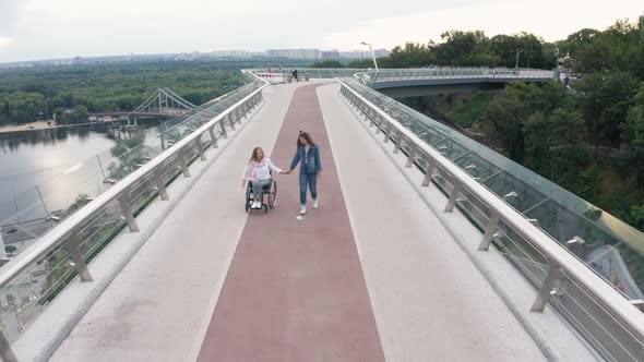 Aerial Shot of Girl Walking with Mom on Wheelchair