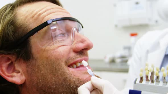 Female dentist showing teeth shades to male patient