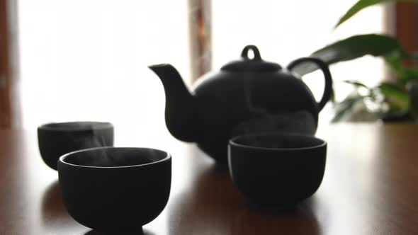 minimal background of a green japanese tea set with steam coming out of the cups, on a wooden table,