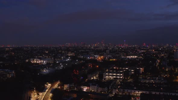 Aerial dolly forward drone shot towards central London Skyline over residential buildings at night