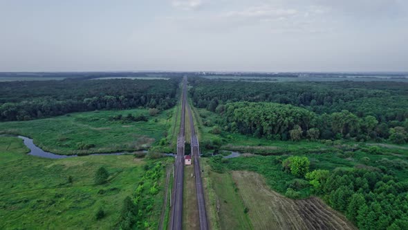 Small River Flows Smoothly Between Green Fields and a Railway Bridge