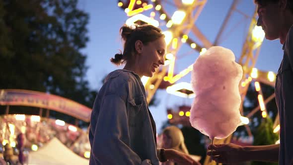 Young Couple Dating Meeting at the Amusement Park Male Bring a Cotton Candy to Her Girlfriend