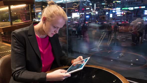 Woman Using Pad in Cafe By Window with City View