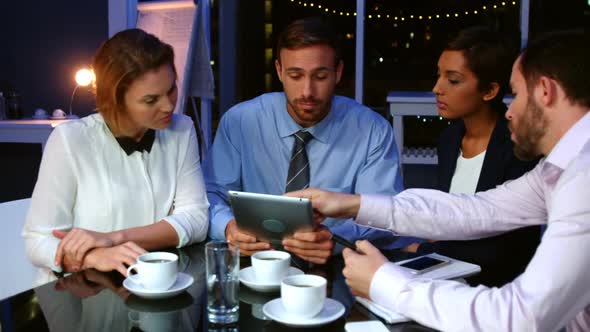 Businesspeople discussing over digital tablet in office