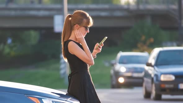 Stylish Woman Driver Standing Near Her Vehicle Talking on Cellphone on City Street in Summer