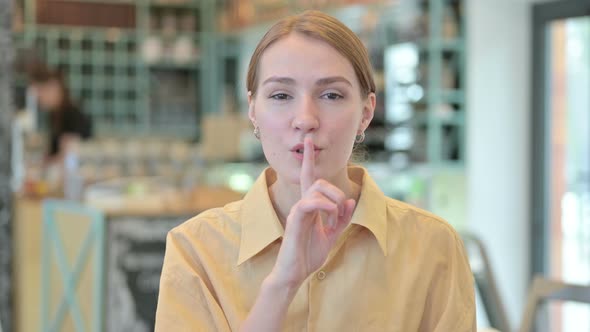 Portrait of Young Woman Putting Finger on Lips, Quiet Sign