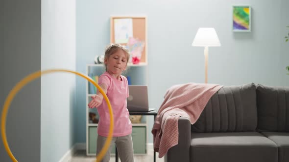 Child Diligently Hulahooping in Bright Room Where There is Notebook