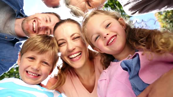 Extended family standing in the park together smiling down at camera