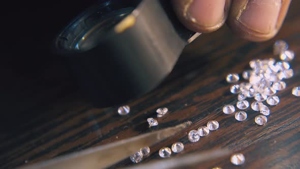 Jeweler Chooses Diamonds with Tweezers on Table Closeup