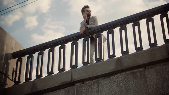 Businessman Stands On Bridge And Talking On Mobile Phone.Freelancer Cellphone Calling Online Meeting