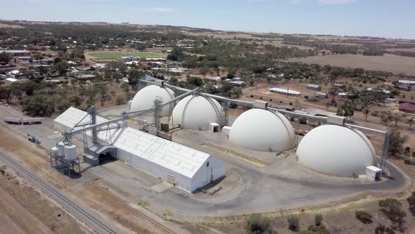 Four dome silos ready to store harvested grain - orbiting aerial view