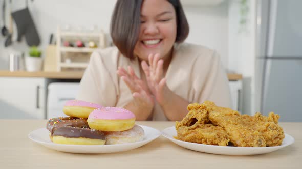 Asian plus size fat girl feeling hungry and ready to eat fried chicken and sweet donut on table.