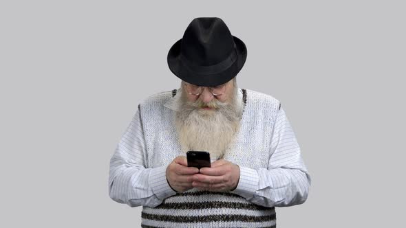 Old Retired Bearded Man Typing Message on His Smartphone