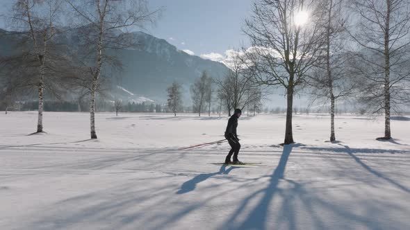 Cross Country Skier Skiing Along Snowy Path Under Sun