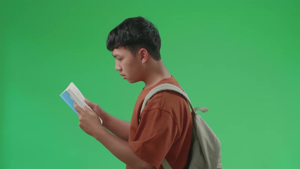 The Side View Of Asian Boy Student Holding And Reading Book While Walking To School On Green Screen