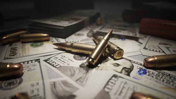 Small pile of ammo bullets on a table covered with countless dollar bills. 4KHD