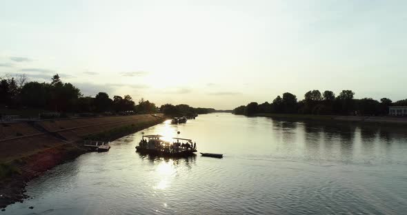 Aerial view of a small boat crossing Drava river at sunset, Osijek, Croatia.