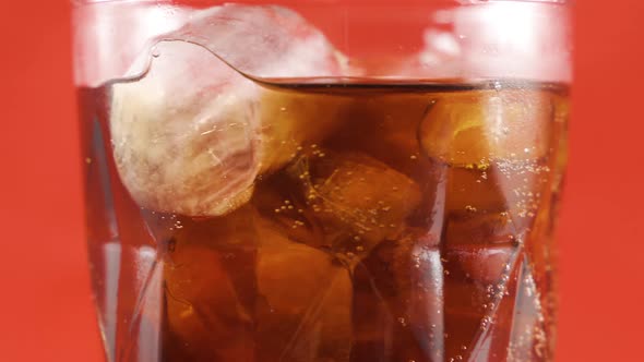 Ice cubes and cola in a swivel glass.